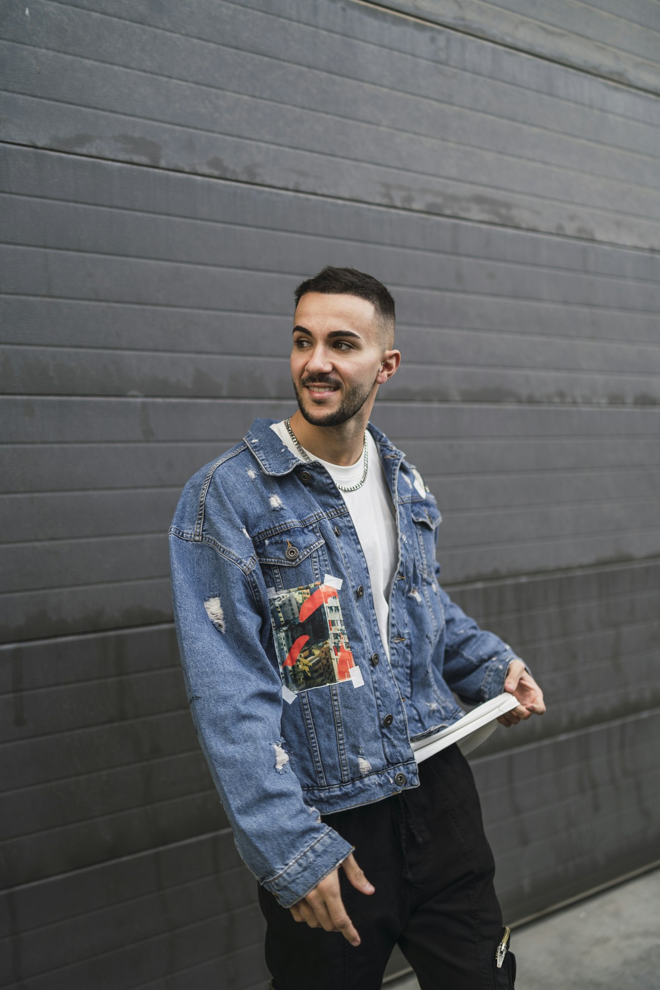Vertical shot of a young trendy male in streetwear posing and smiling